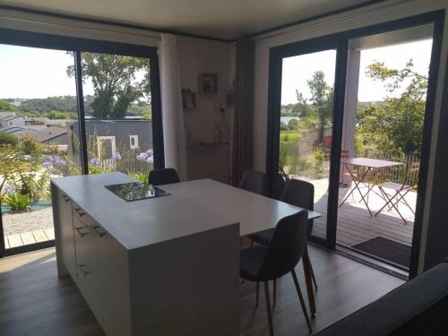 eine Küche mit einem Tisch und Stühlen sowie einen Balkon in der Unterkunft Cottage Nature Piscine partagée Vue Vilaine in Arzal