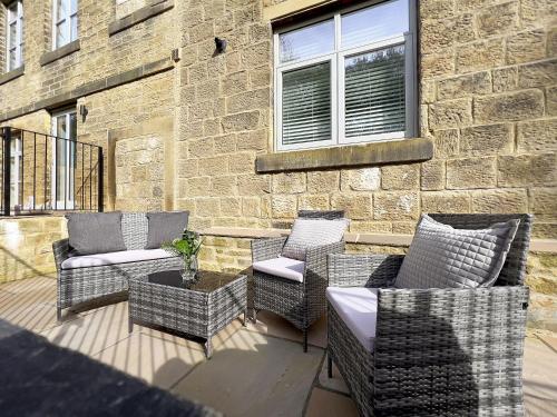 a patio with chairs and a table and a building at The Yorkshire Hosts - The Water Mill in Haworth