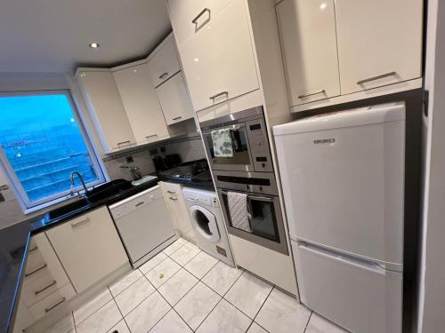a kitchen with white cabinets and a sink and a dishwasher at Serene Ocean Side Apartment BTN in Brighton & Hove