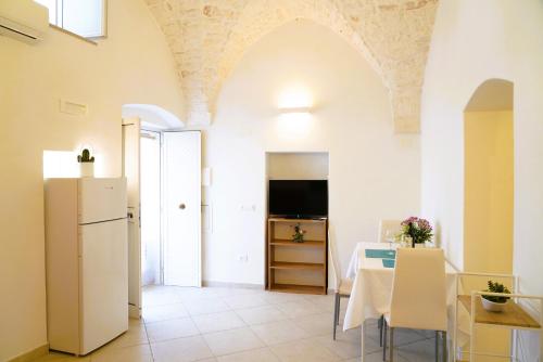 Una cocina y un comedor con una mesa y un refrigerador. en La casetta in pietra - nel CUORE di OSTUNI, en Ostuni