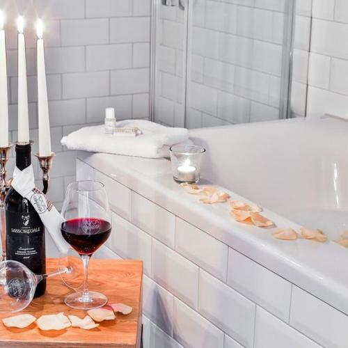 a bottle of wine and a glass of red wine next to a tub at Hotel Utspann Schafflund in Schafflund