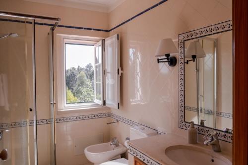 baño con lavabo y aseo y ventana en Magnolia B&B, en Leiria