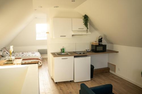a small kitchen with white cabinets and a bed at TC Residences - Charmant Appartement in Saint-Quentin