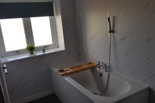 a bathroom with a bath tub and a window at McConaghys Glenside Farmhouse Whitepark Bay in Ballintoy