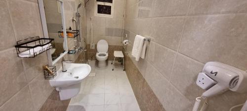 uma casa de banho com um WC branco e um lavatório. em ركن داري للشقق المخدومة em Al Majmaah