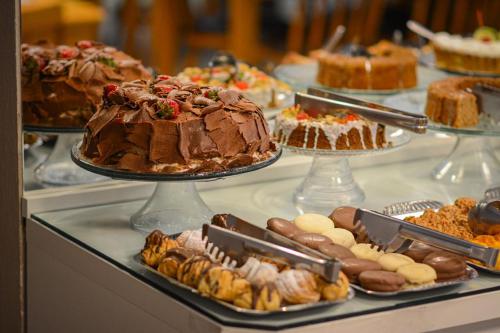 uma mesa cheia de diferentes tipos de bolos e doces em Cammino Della Serra em Canela