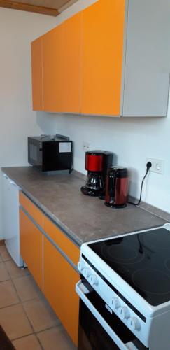a kitchen with orange cabinets and a stove top oven at Ferienwohnung Obhausen bei Querfurt in Obhausen