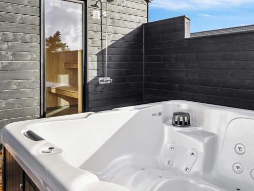 y baño con bañera blanca y azulejos negros. en Holiday home Rømø XV en Kongsmark