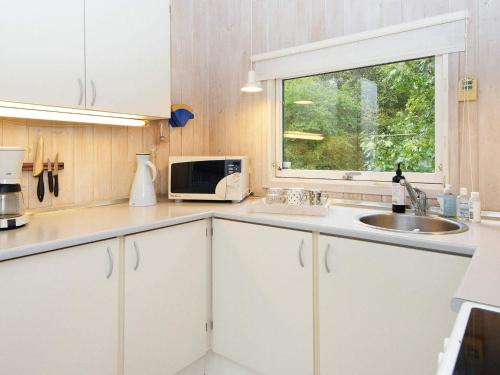 d'une cuisine avec des placards blancs, un évier et une fenêtre. dans l'établissement Holiday home Fårvang VII, à Fårvang