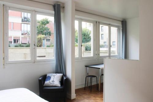 um quarto com uma cama, uma secretária e janelas em 30 m 2 steps from the center of Vanves em Vanves