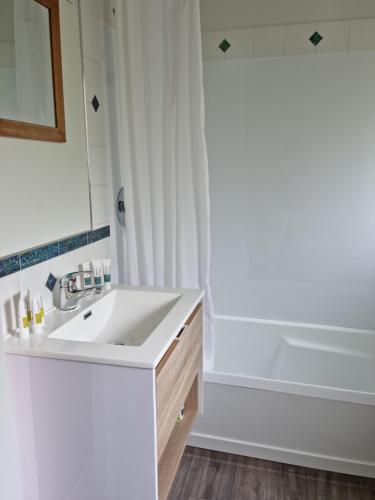 a white bathroom with a sink and a tub at Methven Motel & Apartments in Methven