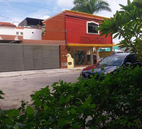 a car parked in front of a red building at Hermosa casa cuatro recámaras independientes CA in Mérida