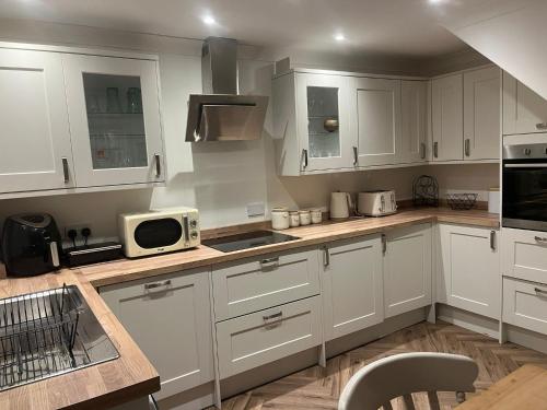 a kitchen with white cabinets and a microwave at The cosy beach House in Llanelli