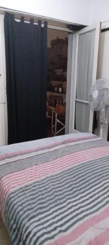 a bed with a striped blanket in a room at 8B Ambiente y medio con Balcon in Mar del Plata