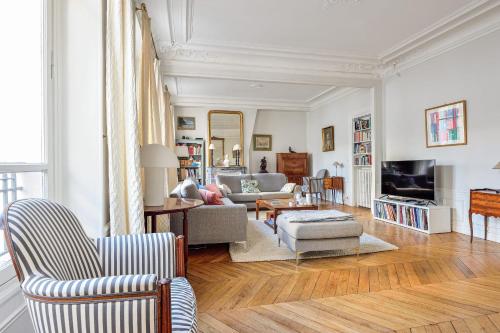 un salon avec un canapé et une télévision dans l'établissement Appartement Panel - Welkeys, à Neuilly-sur-Seine