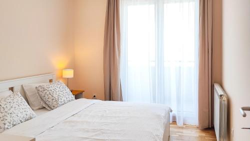 a bedroom with a white bed and a large window at FilinHome Papa Suite 5 in Novi Sad