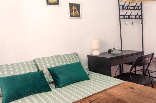 habitación en Alicante, Benalua في أليكانتي: غرفة نوم مع أريكة مع وسائد خضراء ومكتب