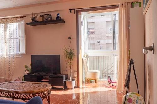 habitación en Alicante, Benalua في أليكانتي: غرفة معيشة فيها تلفزيون ونافذة كبيرة