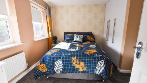a bedroom with a bed with a blue and yellow comforter at 3 Bedroom House close to city centre in Liverpool