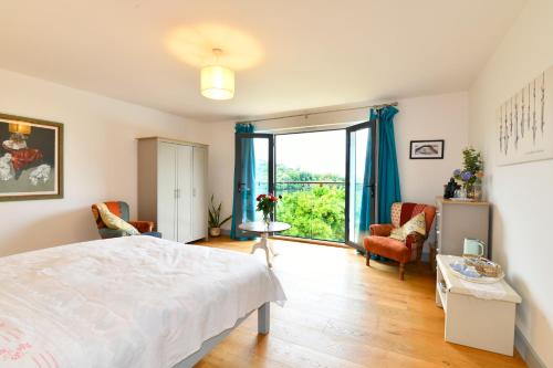 a bedroom with a bed and a large window at Water Edge in Dittisham