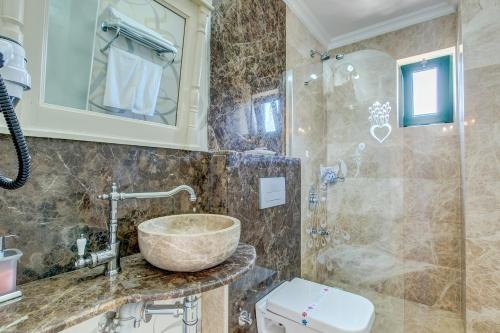 a bathroom with a stone sink and a shower at Cunda Esen Hotel in Ayvalık