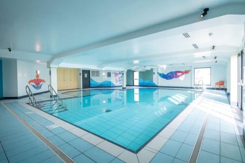 a large swimming pool with two chairs in a building at Beachside Lighthouse 14 in Lossiemouth