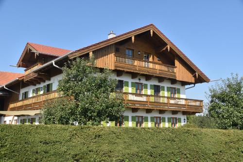 ein großes Holzhaus mit Balkon auf einem Hügel in der Unterkunft Ferienwohnung beim Hainz in Dietramszell