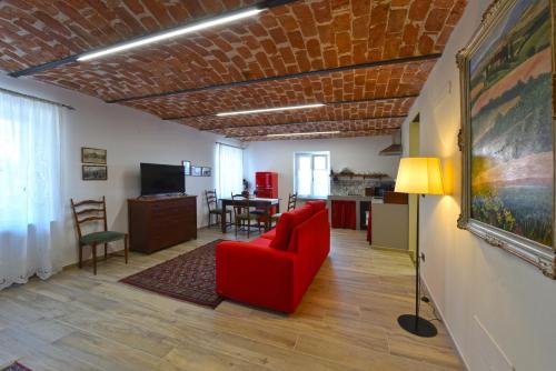 Il comprend un salon avec une chaise rouge et une cuisine. dans l'établissement Casa Valentina 1902, à Montegrosso dʼAsti