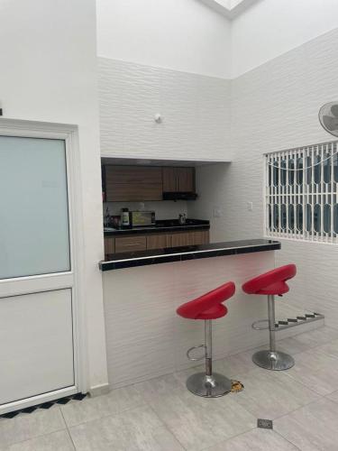 une cuisine avec deux tabourets rouges devant un comptoir dans l'établissement HOTEL POSADA DON JOSE, à Aguachica