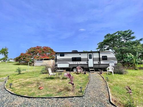 an rv parked in a field with a table and chairs at Camper de Camaseyes in Aguadilla