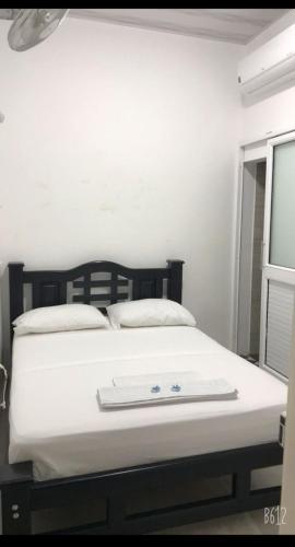 Cama blanca en habitación con ventana en HOTEL POSADA DON JOSE, en Aguachica