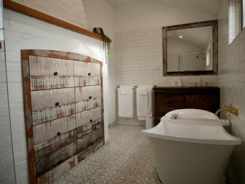 La salle de bains est pourvue d'une baignoire, d'un lavabo et d'un miroir. dans l'établissement Old Koondrook Bakery, à Koondrook
