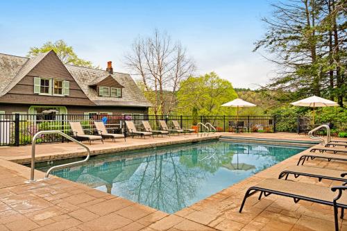 a swimming pool with chairs and umbrellas next to a house at A1 at Castle Hill - Apartment in Cavendish
