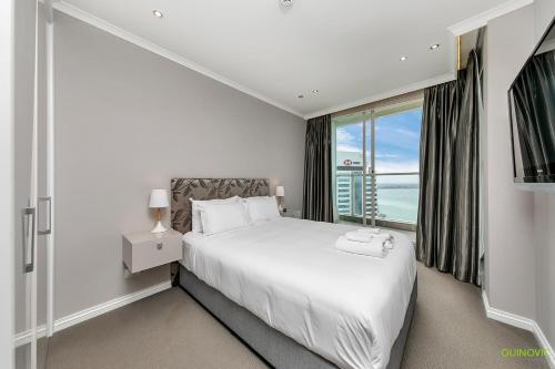 - une chambre avec un lit blanc et une grande fenêtre dans l'établissement QV Luxury with Sea Views (1128), à Auckland