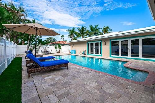 een zwembad met een stoel en een parasol naast een huis bij Beach Paradise * 5 mins walk to beach *chef kitchen *private pool in Riviera Beach