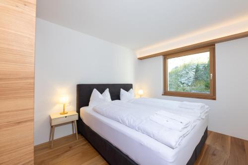 a bedroom with a large white bed with a window at New! Exclusive Apartment 3min to Chantarella Bahn in St. Moritz