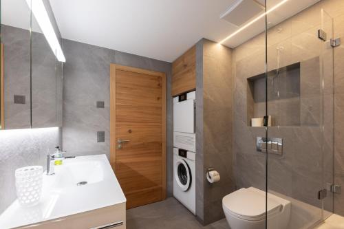 a bathroom with a sink and a washing machine at New! Exclusive Apartment 3min to Chantarella Bahn in St. Moritz