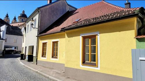 żółty dom z czerwonym dachem na ulicy w obiekcie Altstadthaus Marille mit Innenhofterrasse w mieście Melk