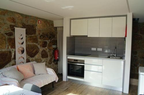 a kitchen with white cabinets and a couch in a room at O Palheiro da Anastácia in Marco de Canaveses