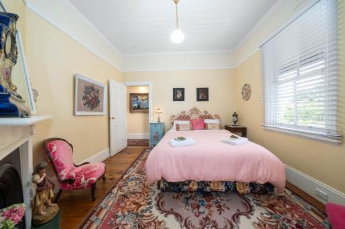 a bedroom with a pink bed and a chair at Berdea in Leura