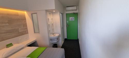 Baño pequeño con puerta verde y aseo en Check Inn Hotel, en Ciudad del Cabo