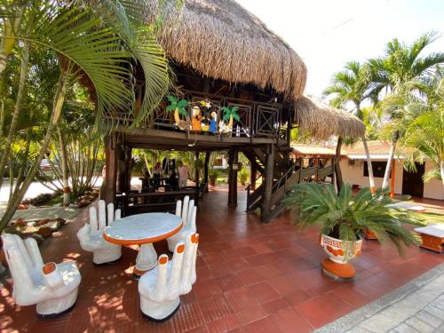 a resort with a table and chairs and a thatch roof at Hotel Mi Rancho Bonito in Sabanalarga