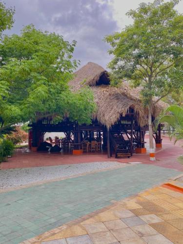a resort with a straw hut with tables and chairs at Hotel Mi Rancho Bonito in Sabanalarga