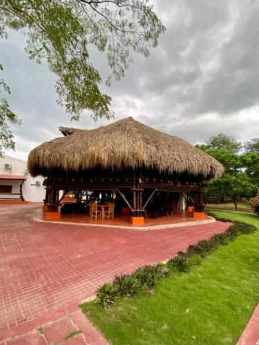 una cabaña con techo de paja y sillas en un patio en Hotel Mi Rancho Bonito, en Sabanalarga