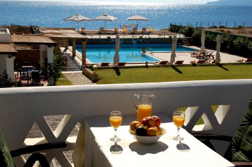 a table with a bowl of fruit and two glasses of orange juice at Vina Beach Hotel in Skiros