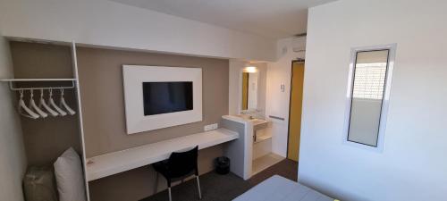 a hotel room with a tv on a wall at Check Inn Hotel in Cape Town