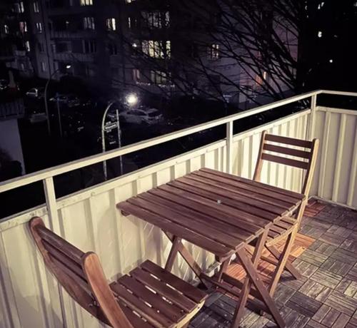 uma mesa de madeira e cadeira numa varanda à noite em Departamento con dos habitaciones em Santiago