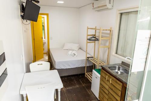 um pequeno quarto com uma cama e um lavatório em Praia Camburi - Studios Kuta em Camburi