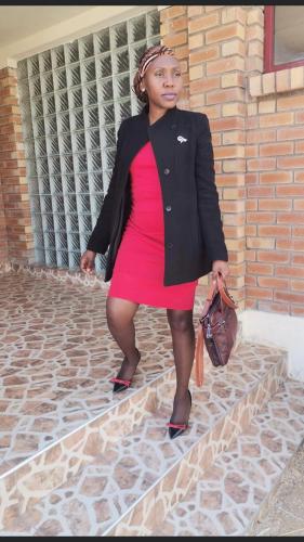 a woman in a red dress and a black jacket at EE Maison Bed and Breakfast in Francistown