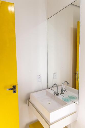 a bathroom with a white sink and a mirror at Praia Camburi - Studios Kuta in Camburi
